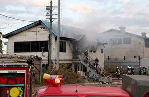 煙があがって消火活動が行われた事務所（中央）＝１１月１４日午後４時過ぎ、妙高市柳井田町