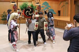 鬼太鼓の団体と記念撮影する観光客＝佐渡市中興