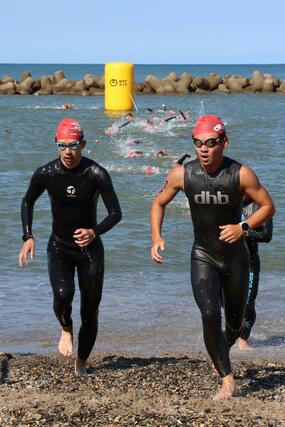 スイムの折り返しのため砂浜に上がる選手たち＝村上市瀬波温泉１