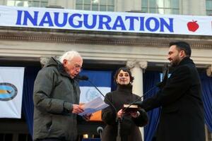 　１日、米ニューヨーク市庁舎で就任式に臨むマムダニ市長（右）と、妻のラマ・ドワジさん（中央）。左はサンダース上院議員（ゲッティ＝共同）