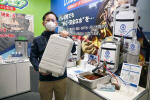 　ケースに入れた非常用浄水器を持つエィアンドエィティーの黒石敏夫さん＝横浜市のパシフィコ横浜