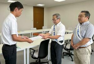 福井県美浜町役場で、町職員(左)に要望書を提出する原告団長の中島孝さん=21日午前