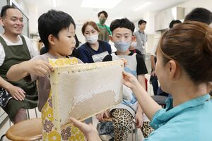蜂蜜がびっしりと詰まった「巣枠」を持つ子どもたち=新潟市東区卸新町3