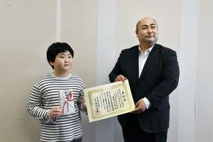 山﨑亮太郎理事長(右)から表彰状などを受け取った星野太郎さん=新潟市中央区西大畑町