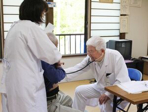 巡回診療で患者を診察する高柳診療所の登坂尚志所長(右)=5月13日、柏崎市高柳町石黒