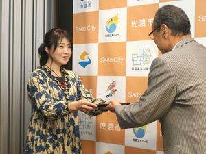 渡辺竜五市長(右)に寄付金の目録を手渡した田村優子さん=佐渡市役所