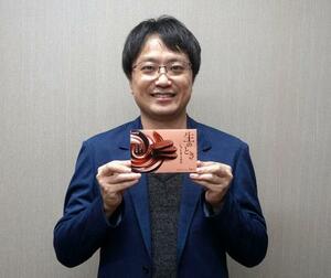 　開発した商品を持つ黒須充春さん。「新商品を製造できる機械を探し歩きました」と話す＝東京都中央区の明治本社