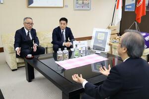 世界的な評価を得た「オホロジン」について花角英世知事(右)に説明する南雲二郎社長(左)=4月24日、県庁