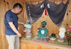 小高集落で大切にされてきた仏像をなでる大渕伸一さん=長岡市西川口