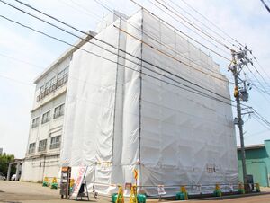 管理が行き届かず、外壁が落下した空き家。白いシートが張られ、周囲に工事用バリケードが立てられていた=6月9日、柏崎市東本町3