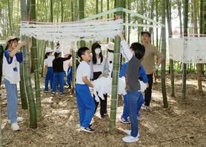 竹に布を巻き付けてあんどんを作る小学生たち=9月5日、田上町原ケ崎新田