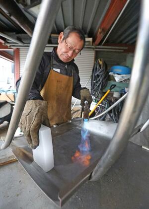 本格的な降雪を控え、スノーダンプにろうを塗る村山和宏さん＝十日町市川治