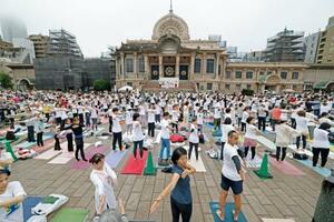 国連が定めた「国際ヨガの日」に、東京都中央区の築地本願寺の境内でヨガを楽しむ参加者=21日午前