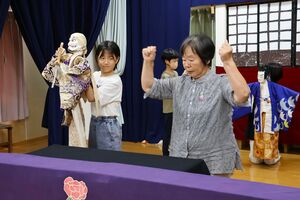 常盤座のメンバーから人形芝居を学ぶ子どもたち=佐渡市泉