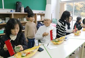 岸義明さん(中央)に柿を使った弁当について説明する児童=佐渡市多田