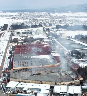煙がくすぶる三幸製菓荒川工場=2022年2月12日、村上市長政
