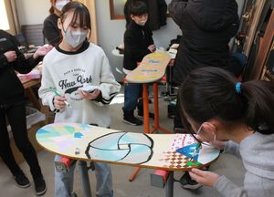 雪板に思い思いの色を塗る戸野目小6年生たち=上越市長面