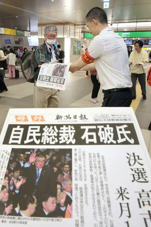 自民党新総裁に石破茂氏選出を伝える本紙号外を受け取る人々=9月27日、新潟市中央区のJR新潟駅