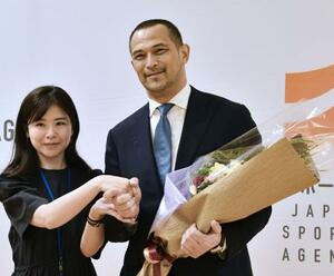 退任に当たり、職員から花束を受け取るスポーツ庁の室伏広治長官(右)=30日午後、東京・霞が関