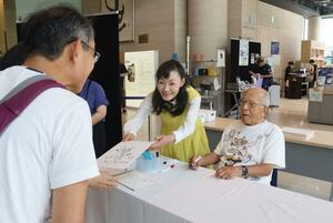 サイン会でイラストを描く、影絵作家の藤城清治さん（右）＝１６日、新潟市中央区万代３