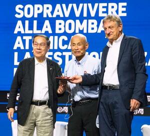 イタリア・リミニのイベントで登壇した箕牧智之さん(中央)と朝長万左男さん(左)=25日(共同)