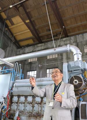 焼夷弾が突き破った屋根の補修跡が残る予備発電機室棟で、当時の様子を語る小林善雄さん=長岡市水道町3