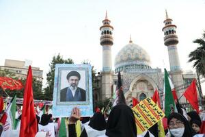 　１２日、イラン・テヘランで最高指導者モジタバ・ハメネイ師を支持して国旗を持つ人たち（ゲッティ＝共同）