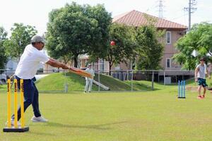 クリケットの体験会でプレーするビネイ・クマールさん(左)=9月、浜松市