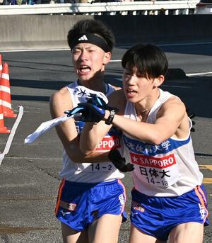 2区を走り、たすきを渡す日体大の山崎丞(左)=横浜市戸塚区
