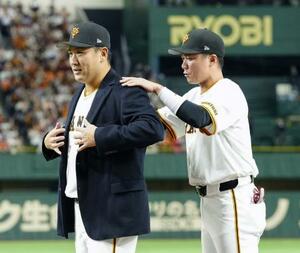 日米通算200勝達成を記念するセレモニーで、坂本勇人内野手(右)から受け取った名球会ブレザーを着る巨人・田中将大投手=1日、東京ドーム