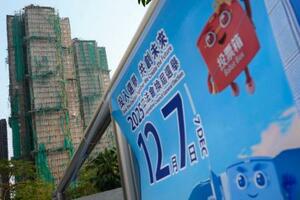 火災のあった高層住宅群(左奥)の近くに掲示された立法会選挙の投票を呼びかけるポスター=5日、香港(共同)