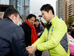 　街頭演説に訪れた人と握手を交わす日本維新の会の藤田共同代表（右）＝２４日午後、東京都江東区