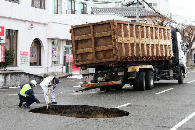 陥没した道路と、はまった車両＝９日、新潟市東区太平４