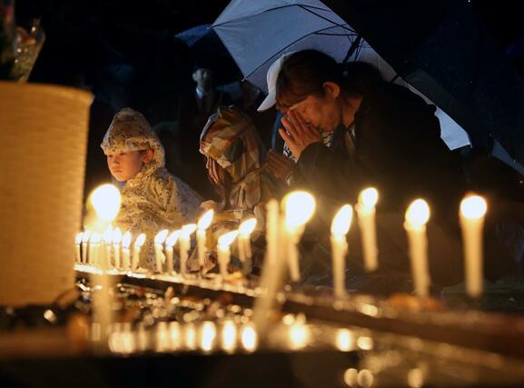 地震で児童が亡くなった跡地に建てられた慰霊碑前で、合掌する集落の住民ら＝１０月２３日午後５時４８分、小千谷市塩谷