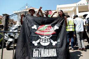 18日、マダガスカル・アンタナナリボで開かれた集会で、海賊旗を掲げるアルソン・ジョセフさん(左)ら(共同)