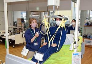 「テクノケア北九州」で介護器具を体験する医療系専門学校生(右)=2025年12月、北九州市(名札にモザイク加工しています)