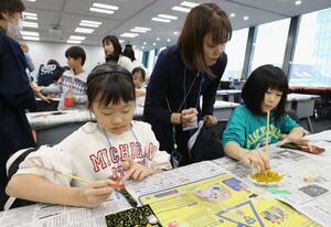 伝統技法の蒔絵でスプーンを作る親子たち=11月24日、新潟市中央区