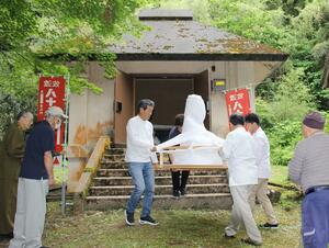 木造阿弥陀如来坐像を運び出す美術院のスタッフら=10日、佐渡市久知河内