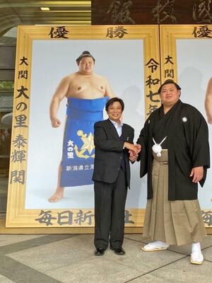 夏場所が始まる前日に開かれた優勝額贈呈式で、握手を交わす田海哲也総監督(左)と大の里=東京都墨田区の両国国技館
