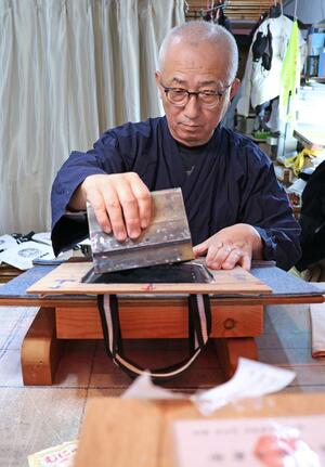 シルクスクリーン印刷でオリジナルトートバッグをつくる品田靖さん。地元イベントの景品として注文を受けた=十日町市松代