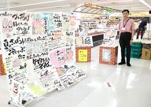自作のポップ広告を前にする吉田店長=8月27日、十日町市山崎のメルシーUモール店