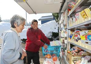常連の買い物客と談笑する武川学さん（右）＝魚沼市板木
