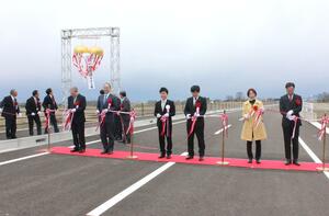 三条北バイパス開通を祝いくす玉が割られ、関係者がテープカットを行った=3月23日、三条市下保内