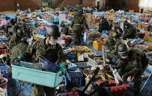 宮城県山元町の小学校には、津波により持ち主が不明となった写真や位牌、ランドセルなどが大量に保管されていた。自衛隊員が思い出の品に付いた泥やほこりを丁寧に落としていた=2011年4月