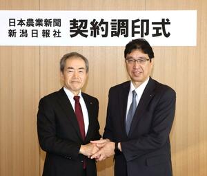 契約調印式で握手する日本農業新聞の田宮和史郎社長(右)と新潟日報社の佐藤明社長=3月21日、新潟市中央区