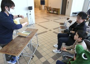 段ボールについてのサイエンスショーで、燃えにくい加工をした段ボールに着火し、効果を学ぶ子どもたち＝上越市の上越科学館