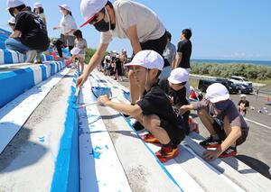 大階段に描かれた下書きにペンキで色を塗る日和山小の児童ら=新潟市中央区西船見町の西海岸公園