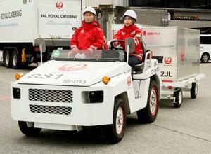 　駐機場で貨物けん引車を運転するミャンマー国籍のテッ・ウェー・フウさん（右）＝２１日午後、成田空港