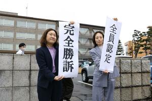 新潟水俣病の第２次行政認定訴訟の判決で「全員認定」「完全勝訴」と書かれた幕を掲げる原告側の弁護士＝１２日、新潟市中央区