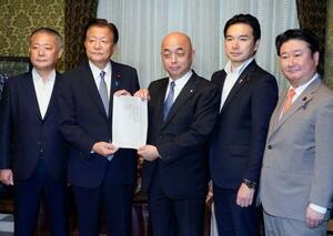 　国民投票法改正案を衆院の築山信彦事務総長（中央）に提出する自民党の新藤義孝氏（左から２人目）ら４党の議員＝５日午後、国会